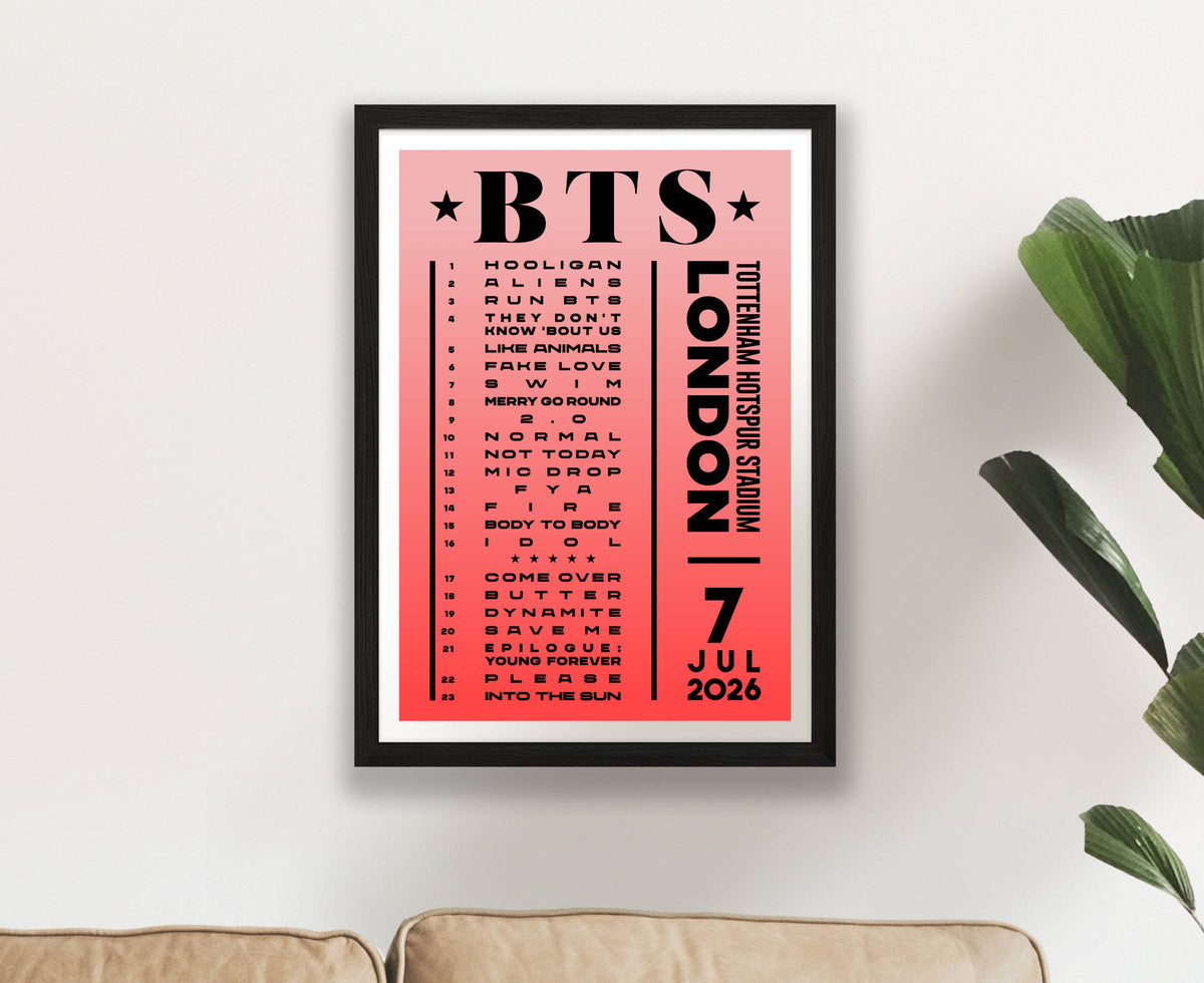 A framed poster featuring the text 'BTS London 7 July 2026' with a list of song titles, hanging on a white wall above a sofa with a green plant visible on the right.