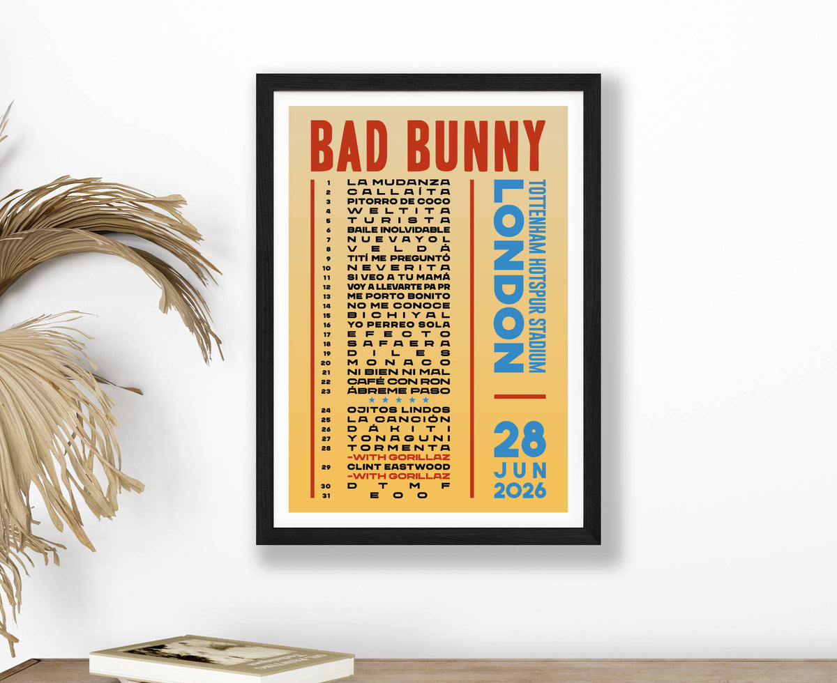 A setlist poster for BAD BUNNY at Tottenham Stadium on 28 June 2026 with red and blue text on a yellow background, framed on a white wall above a sideboard and dried plant. 