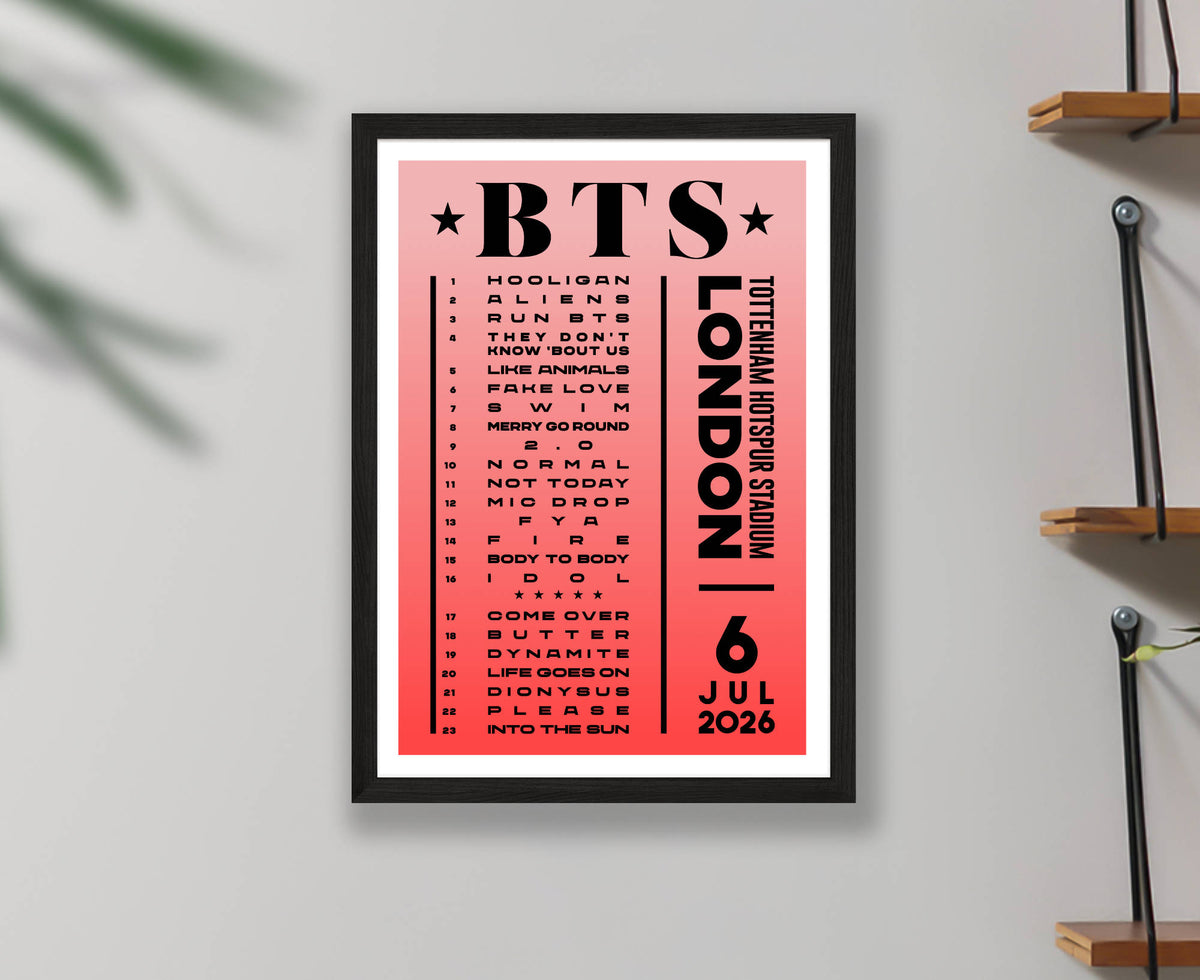 A framed poster featuring a pink and red design with the text 'BTS' and 'Tottenham Hotspur Stadium 6 July 2026' and a list of BTS songs, displayed on a light wall with wooden shelf accents.
