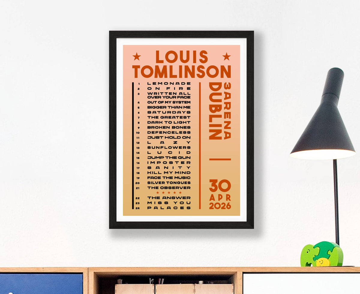 A Louis Tomlinson concert poster print for Dublin on 30 April 2026 in a black frame, hanging on a white wall above a wooden shelf with a black lamp and small green figurines.