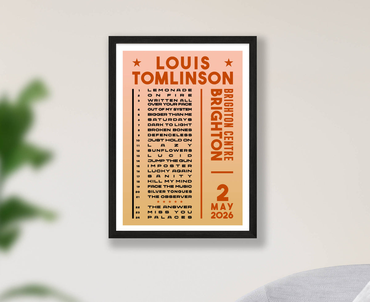 A framed concert poster for Louis Tomlinson at Brighton Centre on 2 May 2026, displayed on a light gray wall with soft green leaves blurred in the background.